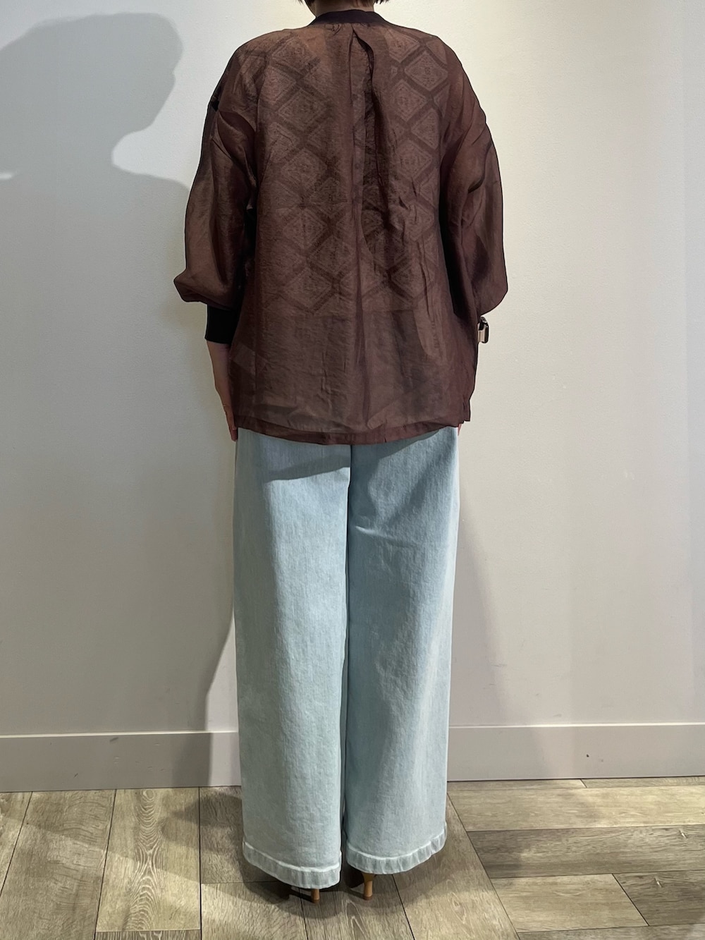 ブラウン系のカーディガン/ボレロ、ホワイト系のベスト、ブルー系のデニムパンツを着用したレディースの夏コーディネートの4枚目の写真