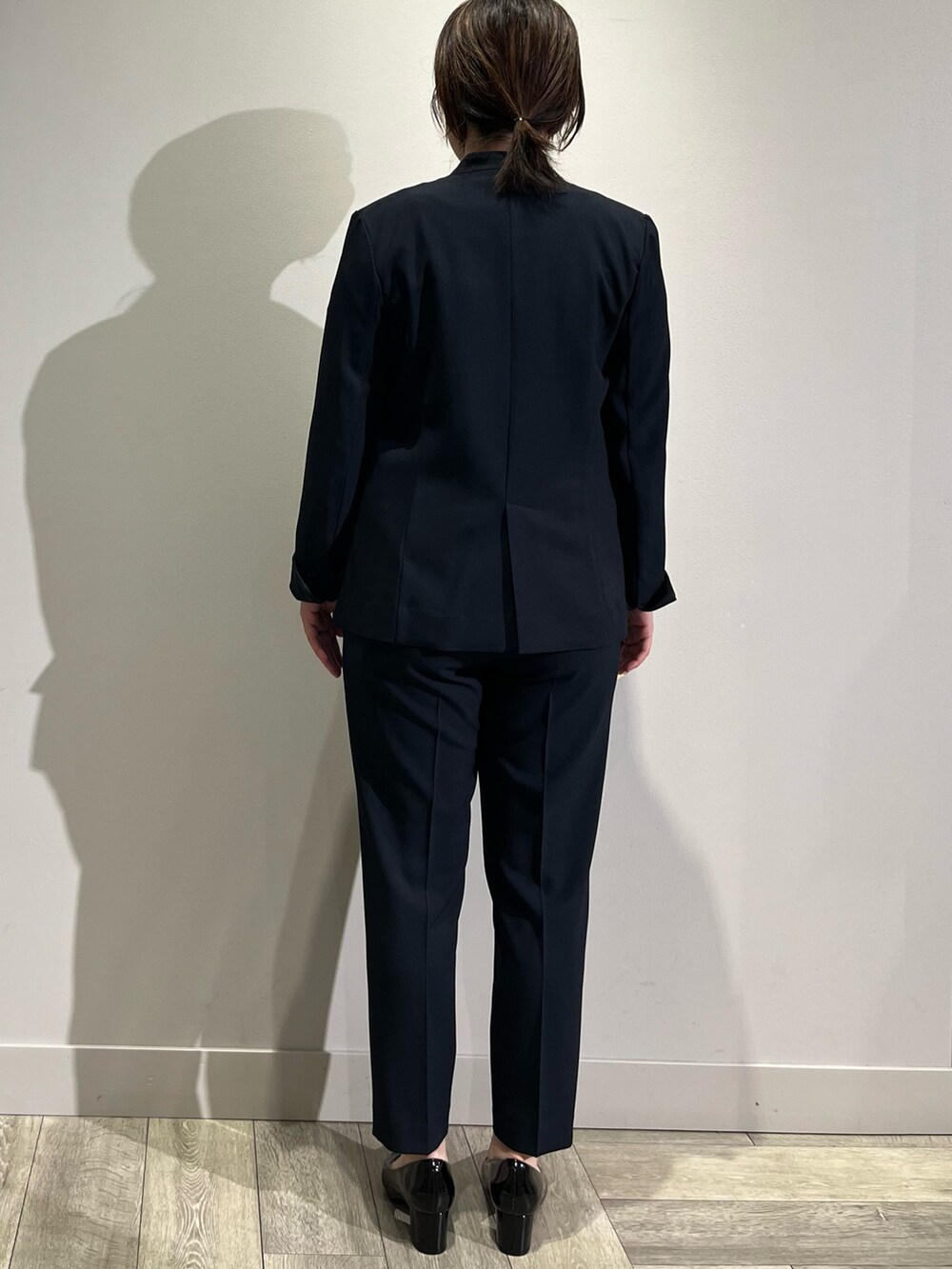 ベージュ系のノーカラーコート、ブルー系のセットアップ、ブルー系のスラックスを着用したレディースの冬コーディネートの5枚目の写真