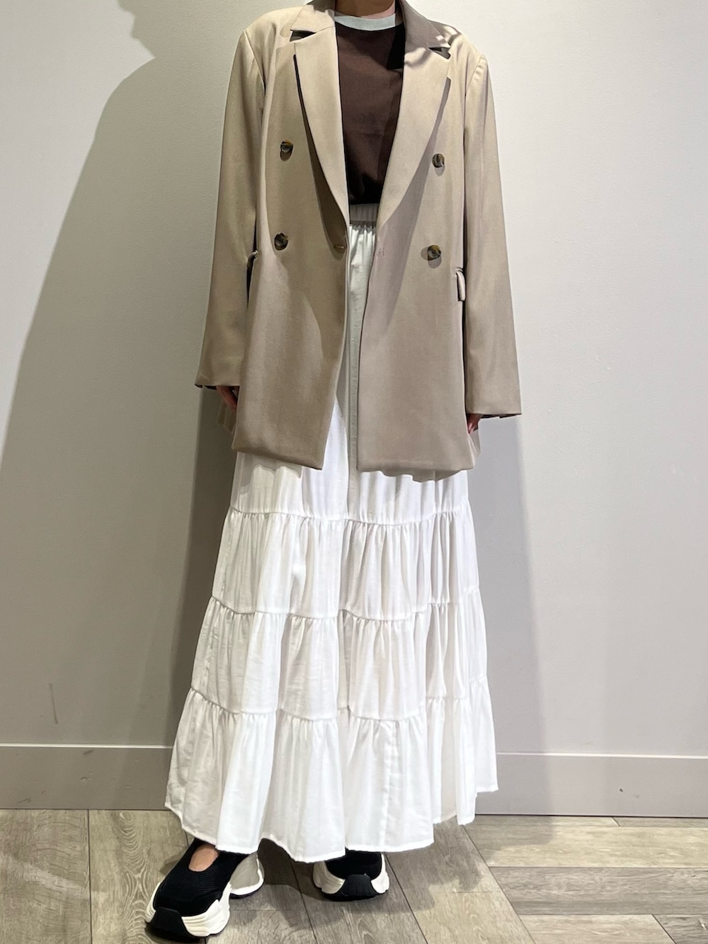 ベージュ系のテーラードジャケット、ホワイト系のスカート、ブラウン系のTシャツ/カットソーを着用したレディースの春コーディネートの2枚目の写真