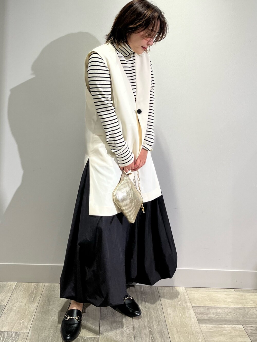 ホワイト系のベスト、ブラック系のスカートを着用したレディースの秋コーディネートの3枚目の写真