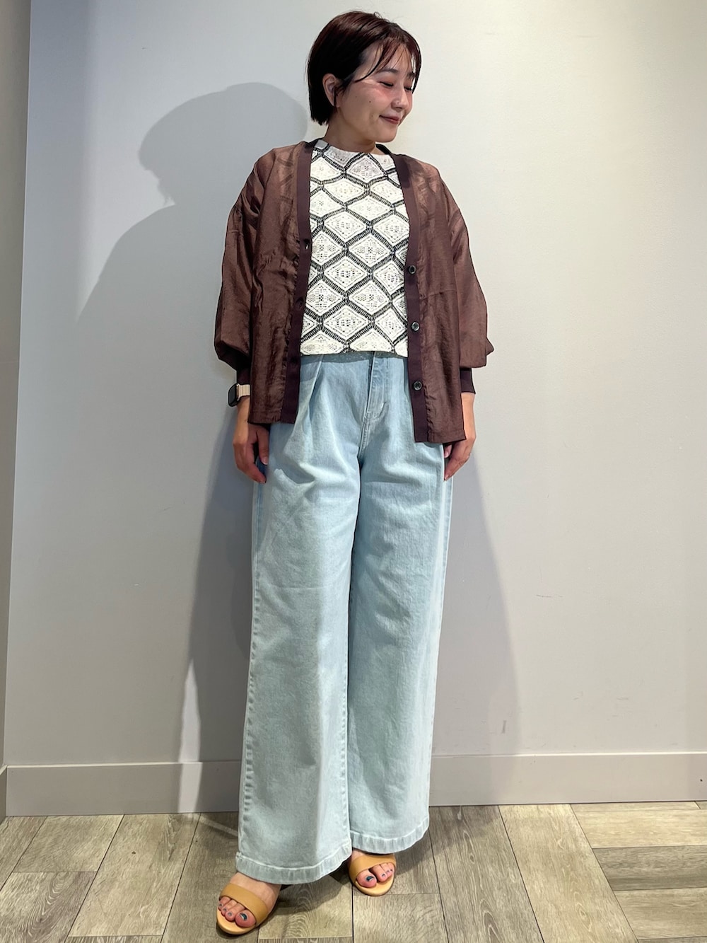 ブラウン系のカーディガン/ボレロ、ホワイト系のベスト、ブルー系のデニムパンツを着用したレディースの夏コーディネートの2枚目の写真