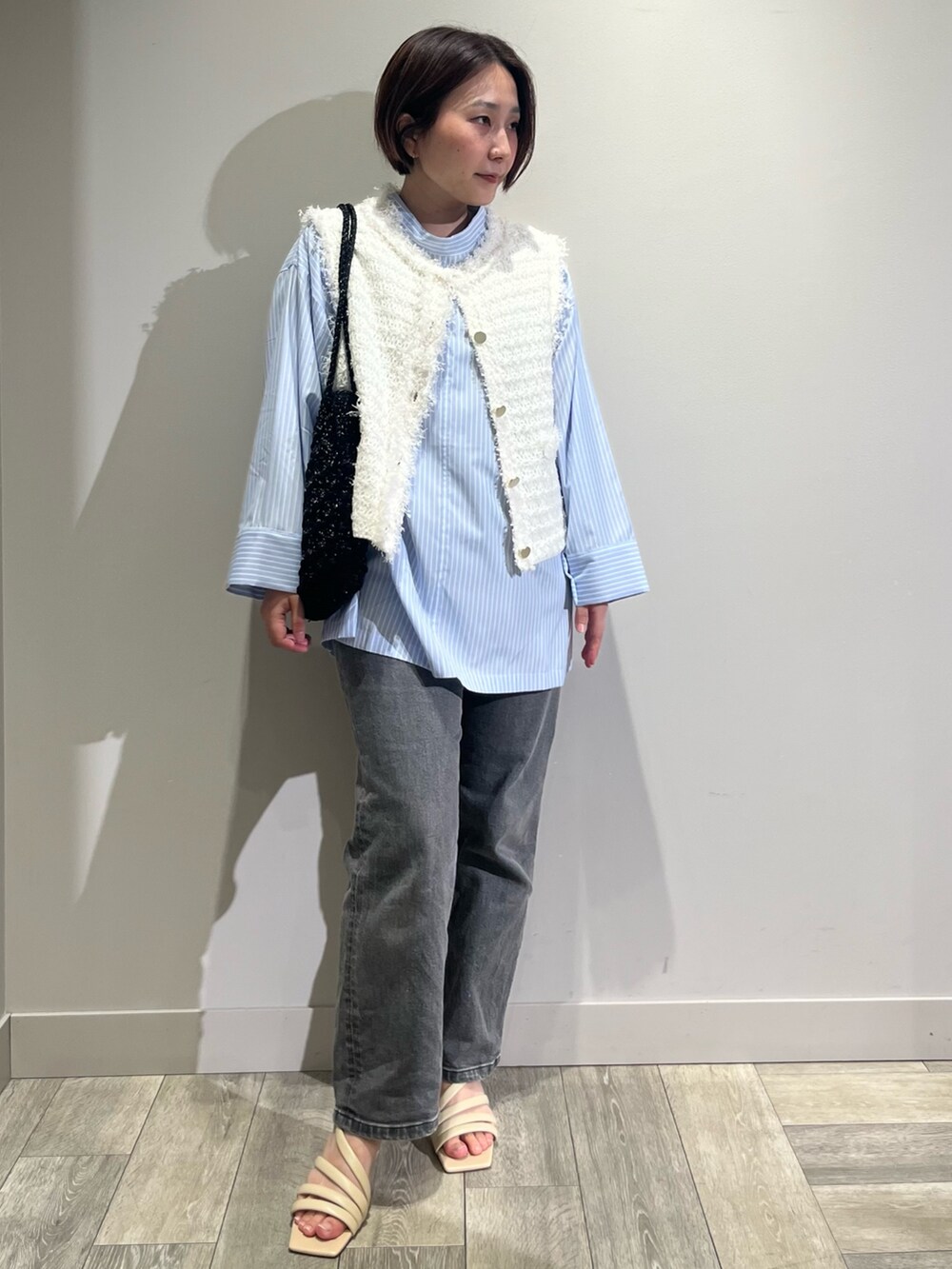 ブルー系のシャツ/ブラウス、ブラック系のデニムパンツ、ホワイト系のベストを着用したレディースの春コーディネートの5枚目の写真