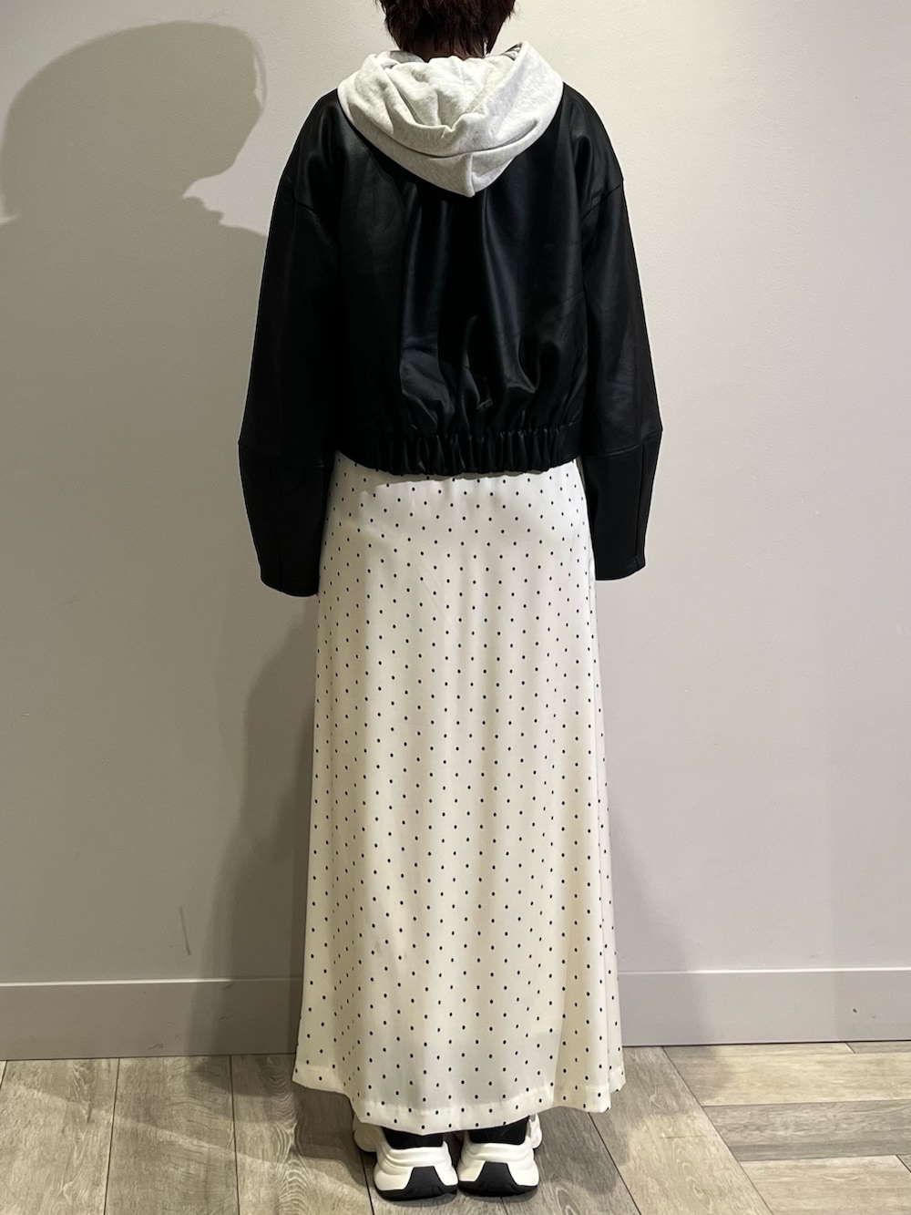 ブラック系のブルゾン、グレー系のパーカー、ホワイト系のスカートを着用したレディースの春コーディネートの4枚目の写真