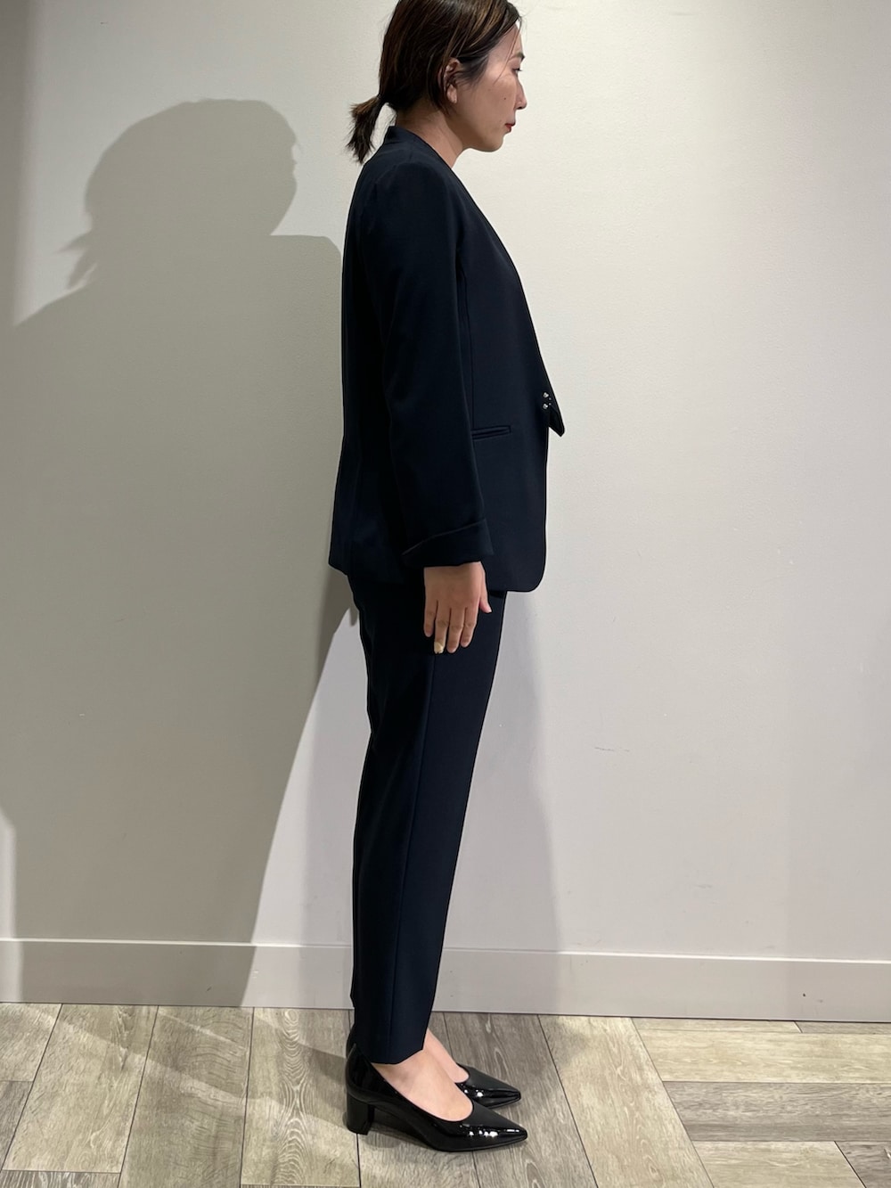 ベージュ系のノーカラーコート、ブルー系のセットアップ、ブルー系のスラックスを着用したレディースの冬コーディネートの4枚目の写真