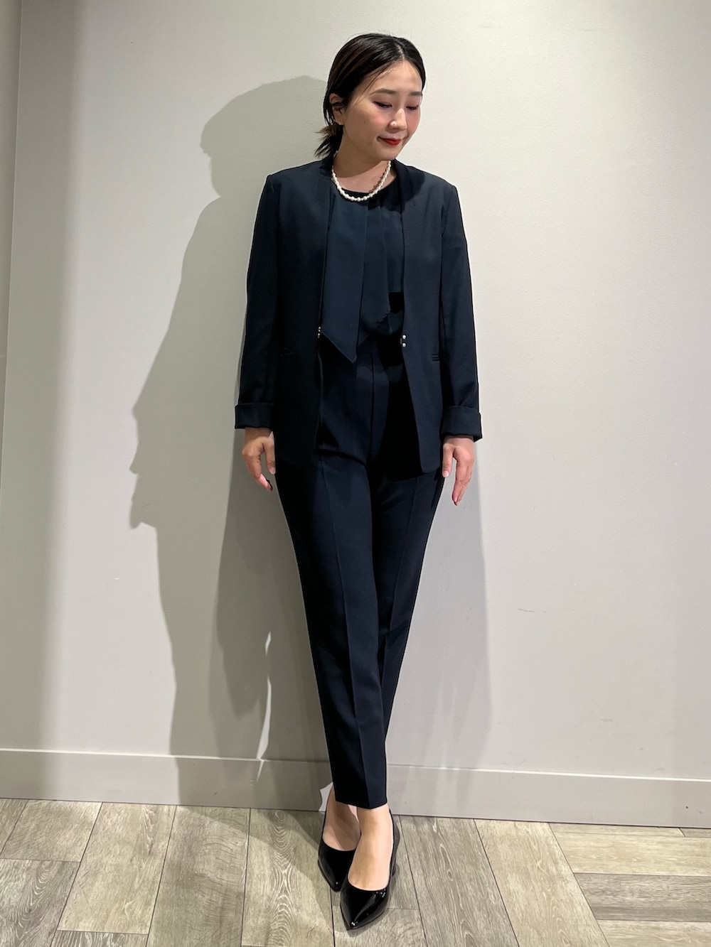 ベージュ系のノーカラーコート、ブルー系のセットアップ、ブルー系のスラックスを着用したレディースの冬コーディネートの3枚目の写真