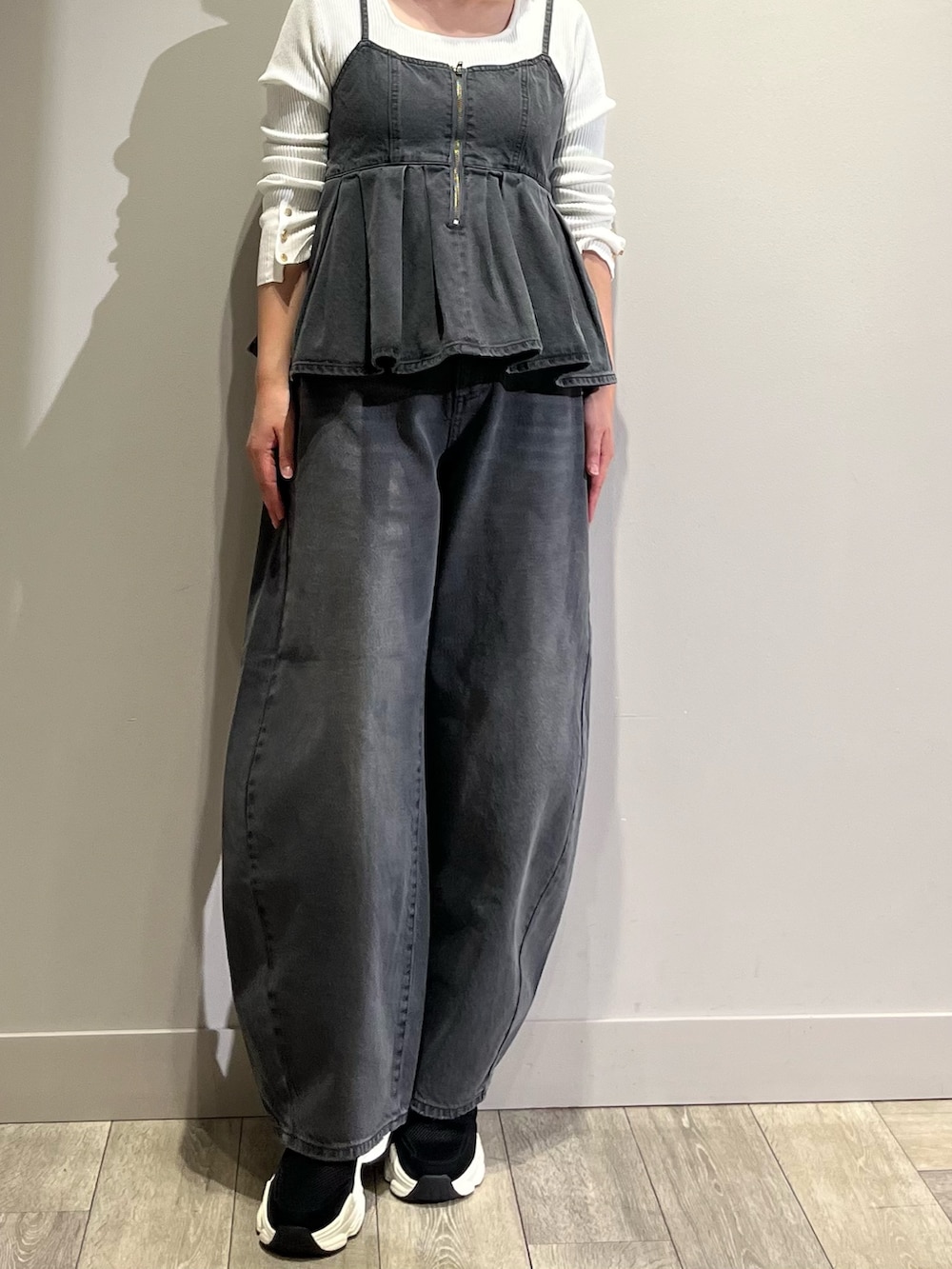 グレー系のキャミソール、グレー系のデニムパンツ、ホワイト系のニット/セーターを着用したレディースの春コーディネートの2枚目の写真