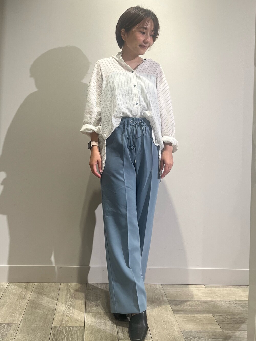 ホワイト系のシャツ/ブラウス、ブルー系のスラックスを着用したレディースの夏コーディネートの2枚目の写真