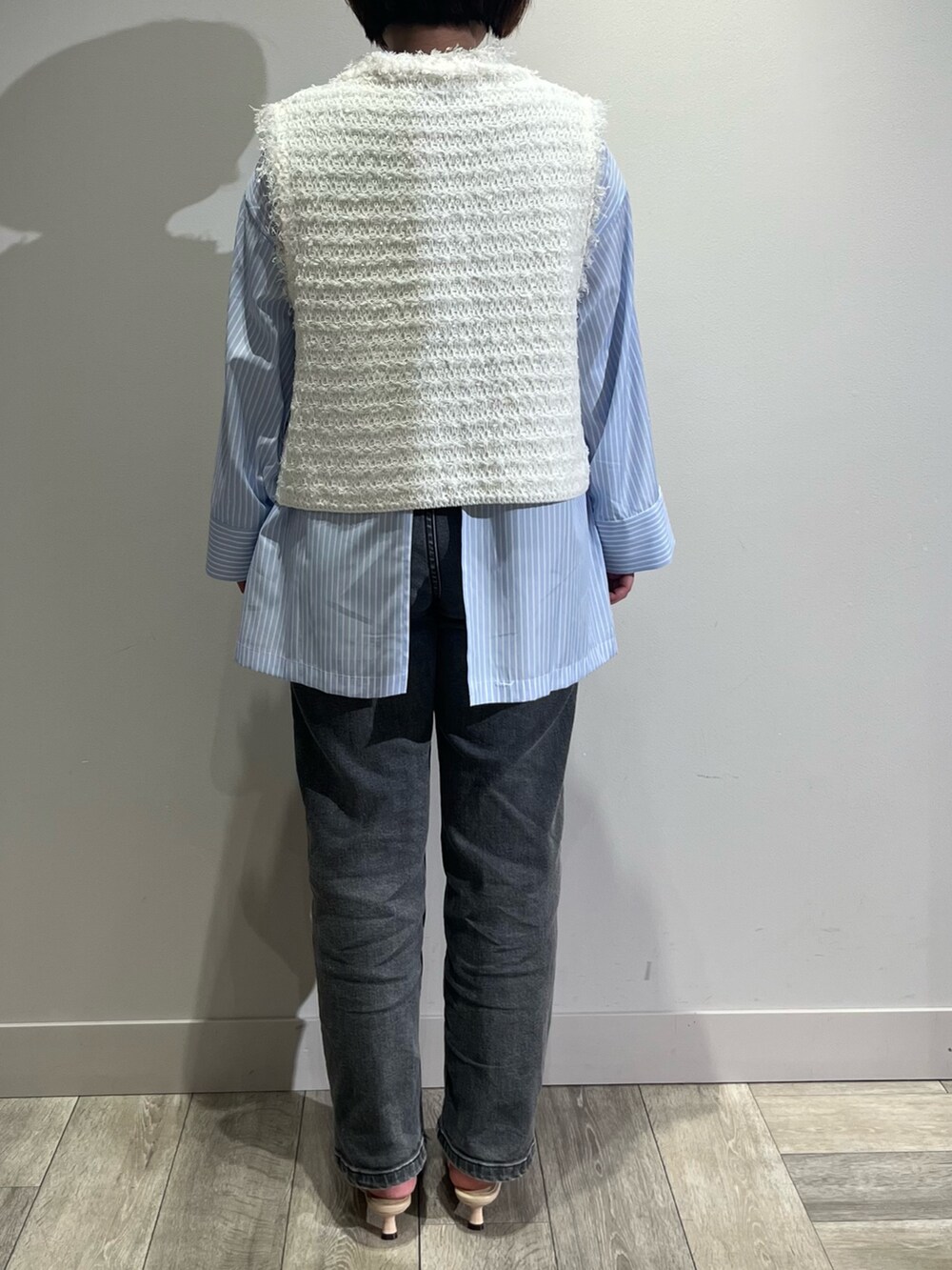 ブルー系のシャツ/ブラウス、ブラック系のデニムパンツ、ホワイト系のベストを着用したレディースの春コーディネートの4枚目の写真