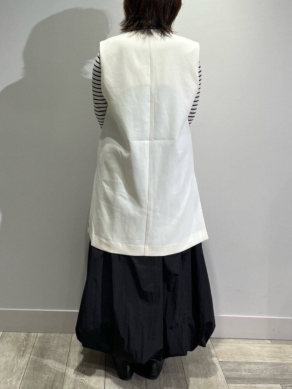 ホワイト系のベスト、ブラック系のスカートを着用したレディースの秋コーディネートの6枚目の写真