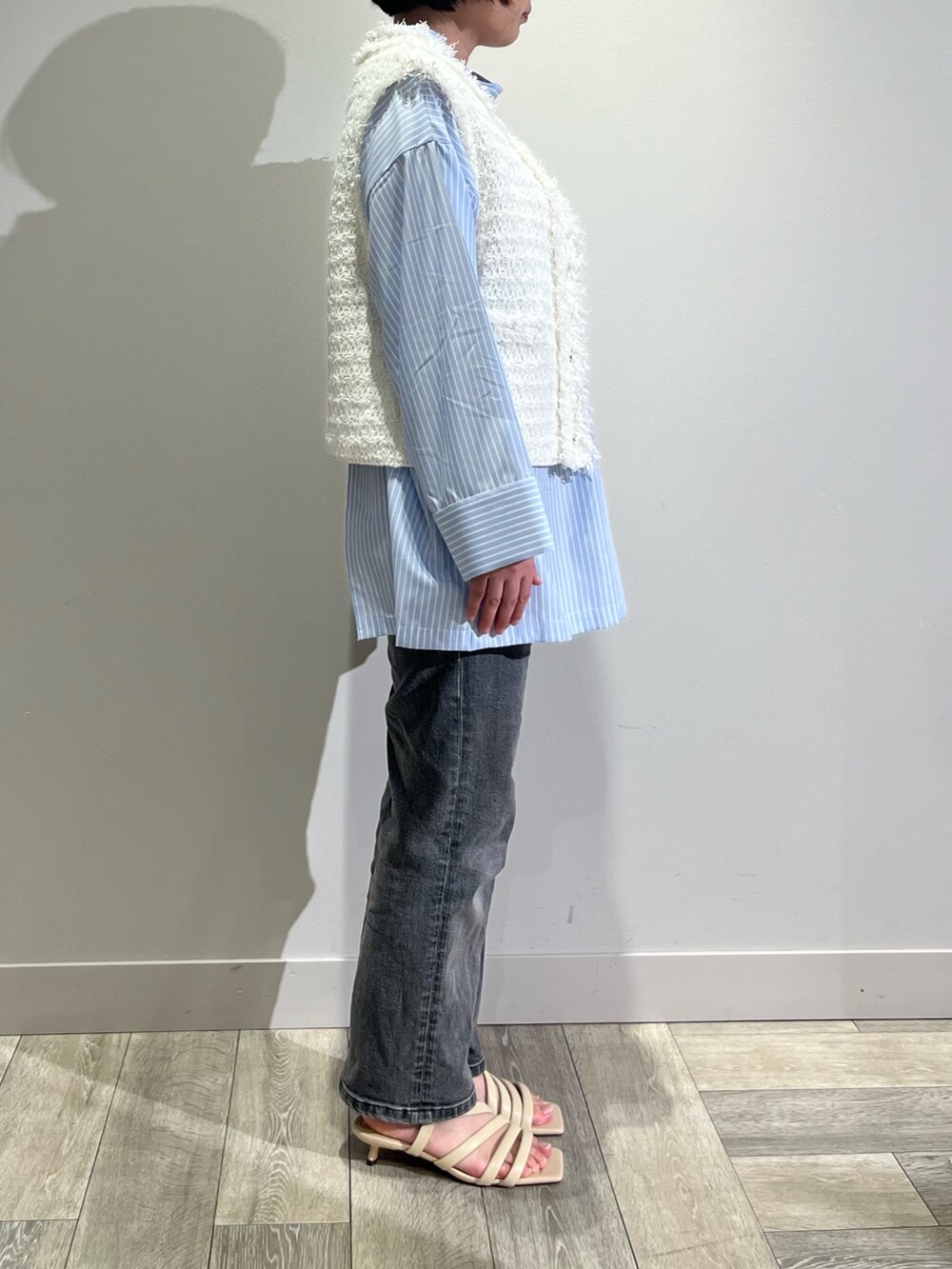 ブルー系のシャツ/ブラウス、ブラック系のデニムパンツ、ホワイト系のベストを着用したレディースの春コーディネートの3枚目の写真