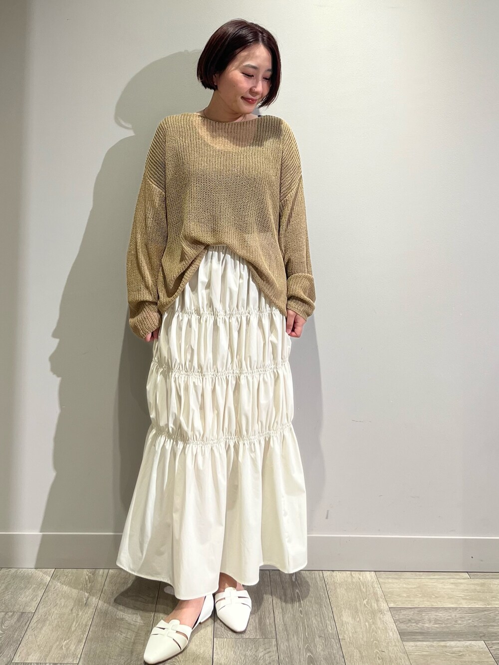 ベージュ系のニット/セーター、ホワイト系のスカート、グリーン系のブルゾンを着用したレディースの春コーディネートの2枚目の写真