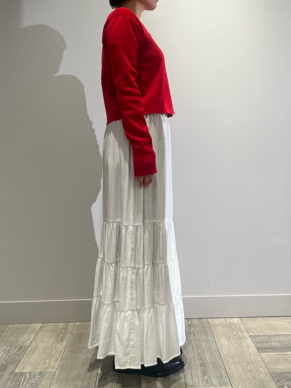 ホワイト系のスカート、ベージュ系のダウンジャケット/コート、レッド系のカーディガン/ボレロを着用したレディースの冬コーディネートの3枚目の写真