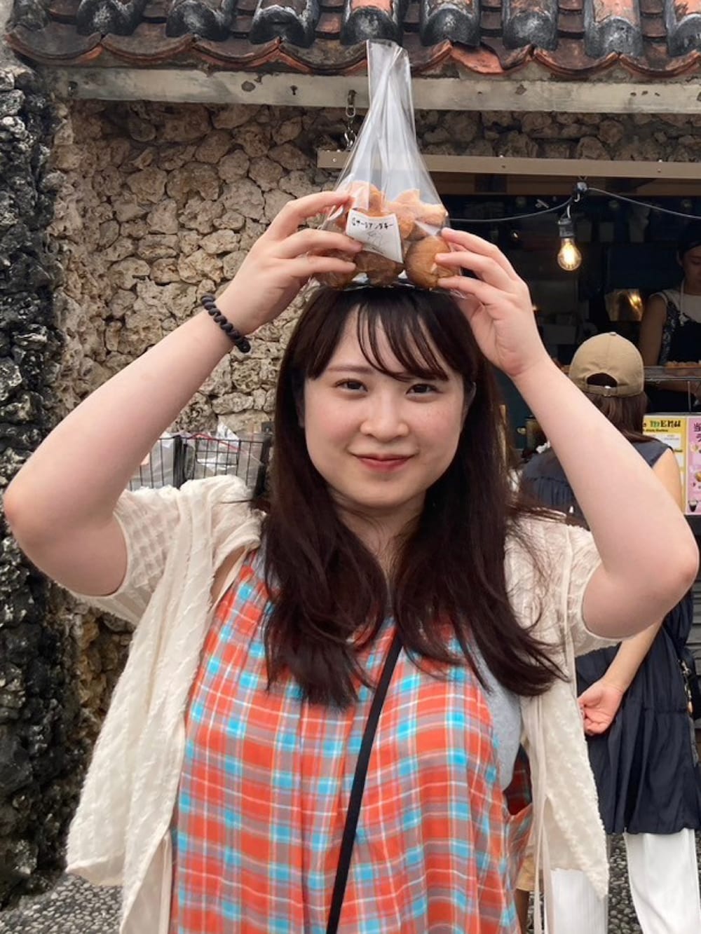 ブラック系のショルダーバッグ、オレンジ系のワンピース、ホワイト系のトップスを着用したレディースの夏コーディネートの3枚目の写真