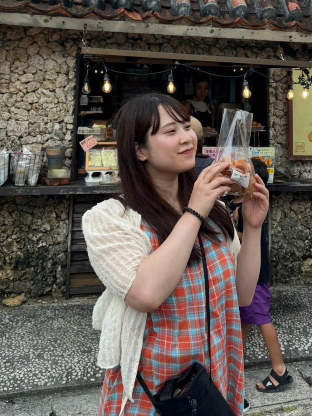 ブラック系のショルダーバッグ、オレンジ系のワンピース、ホワイト系のトップスを着用したレディースの夏コーディネートの2枚目の写真