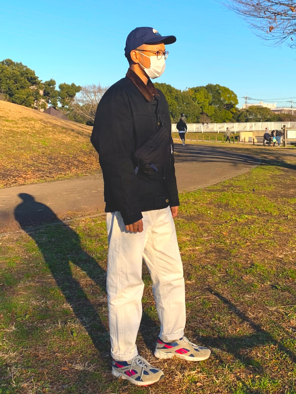 ブルー系のデニムパンツ、ホワイト系のスニーカー、ブラック系のジャケット/アウターを着用したメンズの冬コーディネートの2枚目の写真