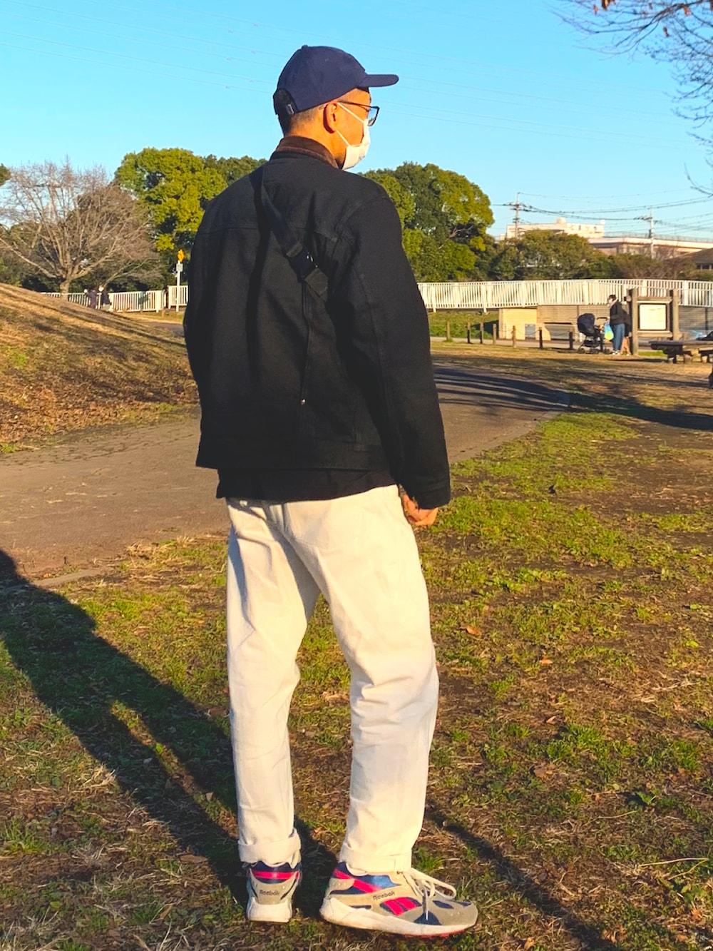 ブルー系のデニムパンツ、ホワイト系のスニーカー、ブラック系のジャケット/アウターを着用したメンズの冬コーディネートの3枚目の写真