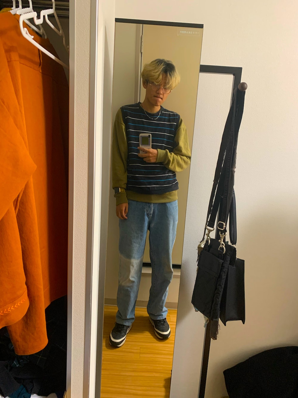 ブルー系のデニムパンツ、ブラック系のスニーカー、ブラック系のベストを着用したメンズの秋コーディネートの2枚目の写真