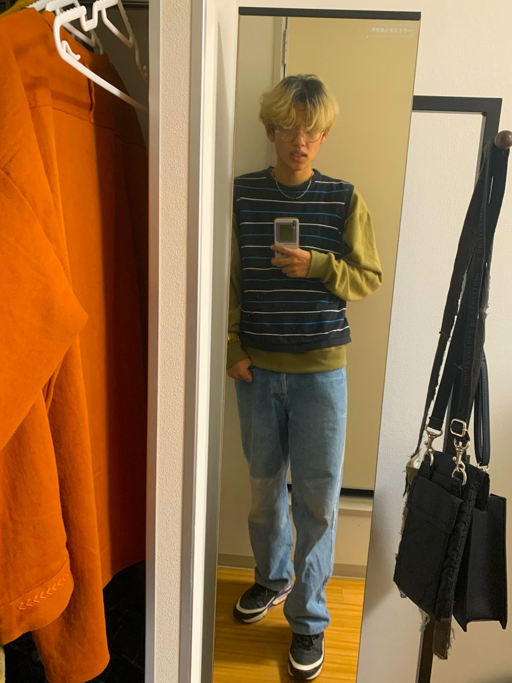 ブルー系のデニムパンツ、ブラック系のスニーカー、ブラック系のベストを着用したメンズの秋コーディネートの3枚目の写真