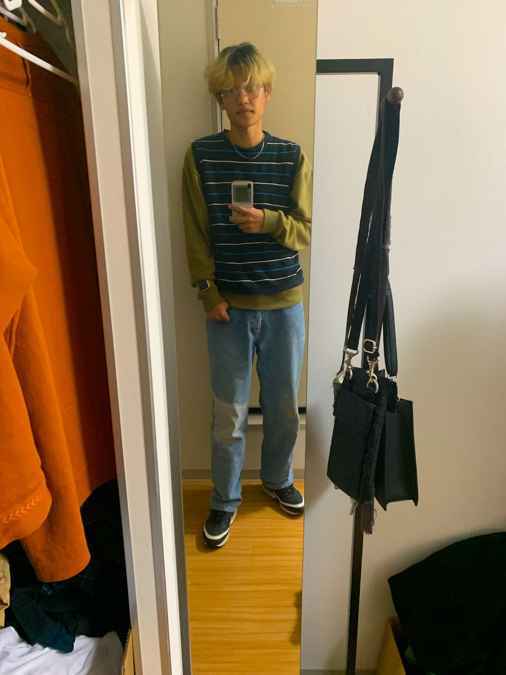 ブルー系のデニムパンツ、ブラック系のスニーカー、ブラック系のベストを着用したメンズの秋コーディネートの4枚目の写真