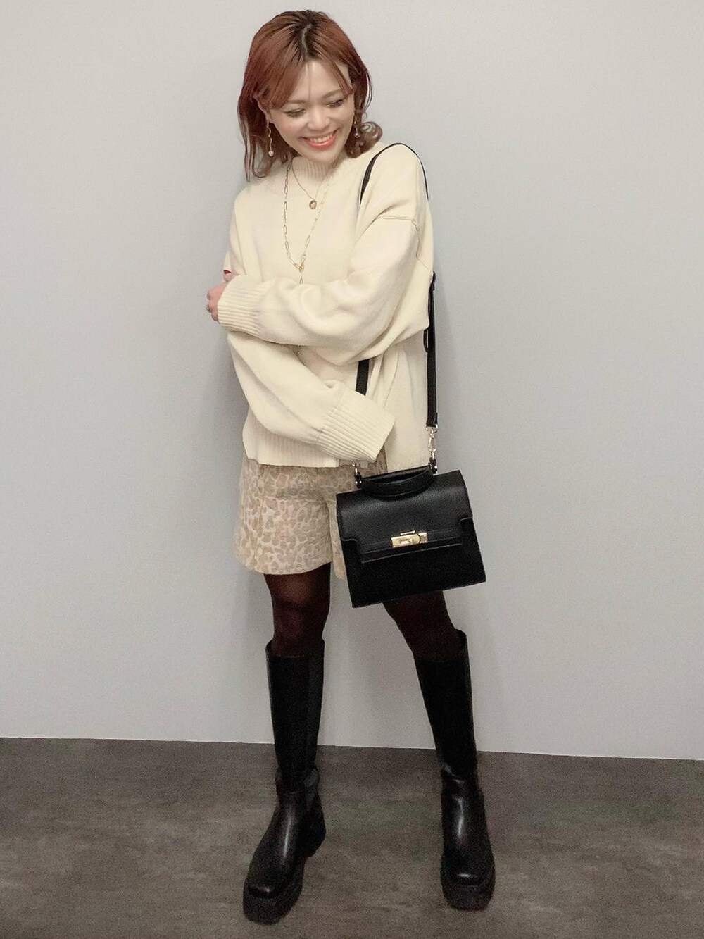 レッド系のハンドバッグ、ホワイト系のニット/セーター、ベージュ系のスラックスを着用したレディースの冬コーディネートの3枚目の写真