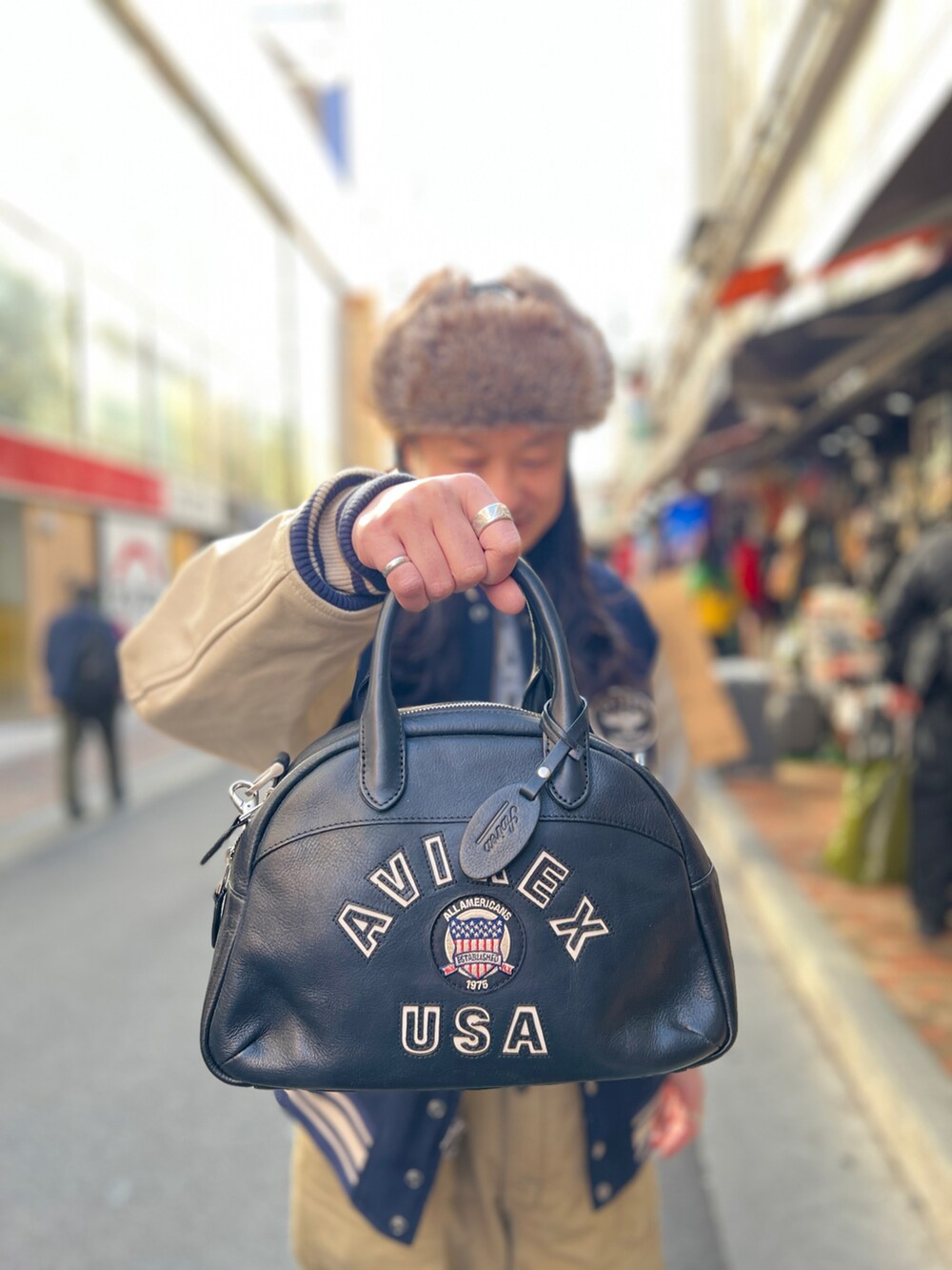 ブルー系のスタジャン、ブラック系のボストンバッグ、グリーン系のキャップを着用したメンズの冬コーディネートの3枚目の写真