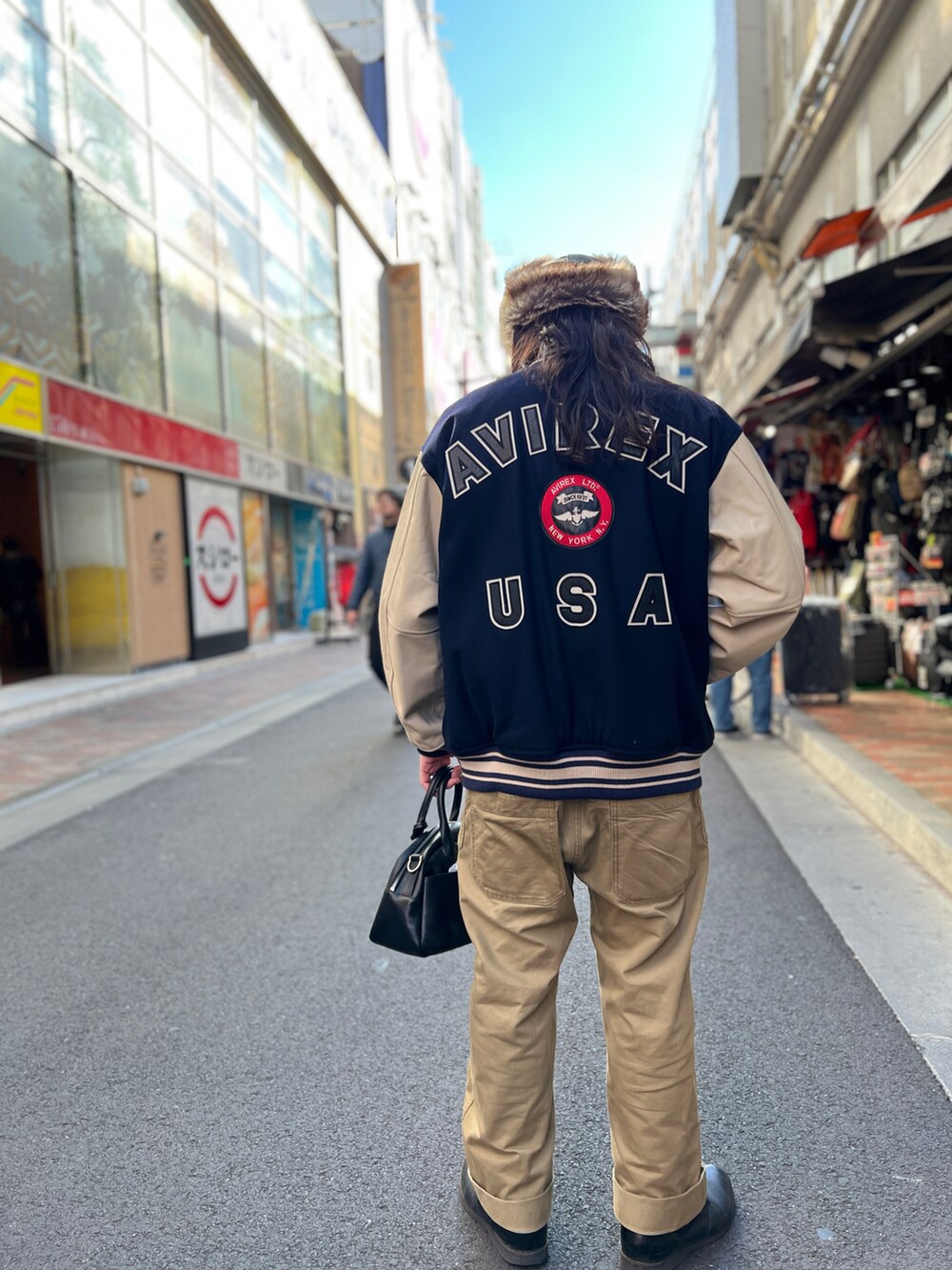 ブルー系のスタジャン、ブラック系のボストンバッグ、グリーン系のキャップを着用したメンズの冬コーディネートの2枚目の写真