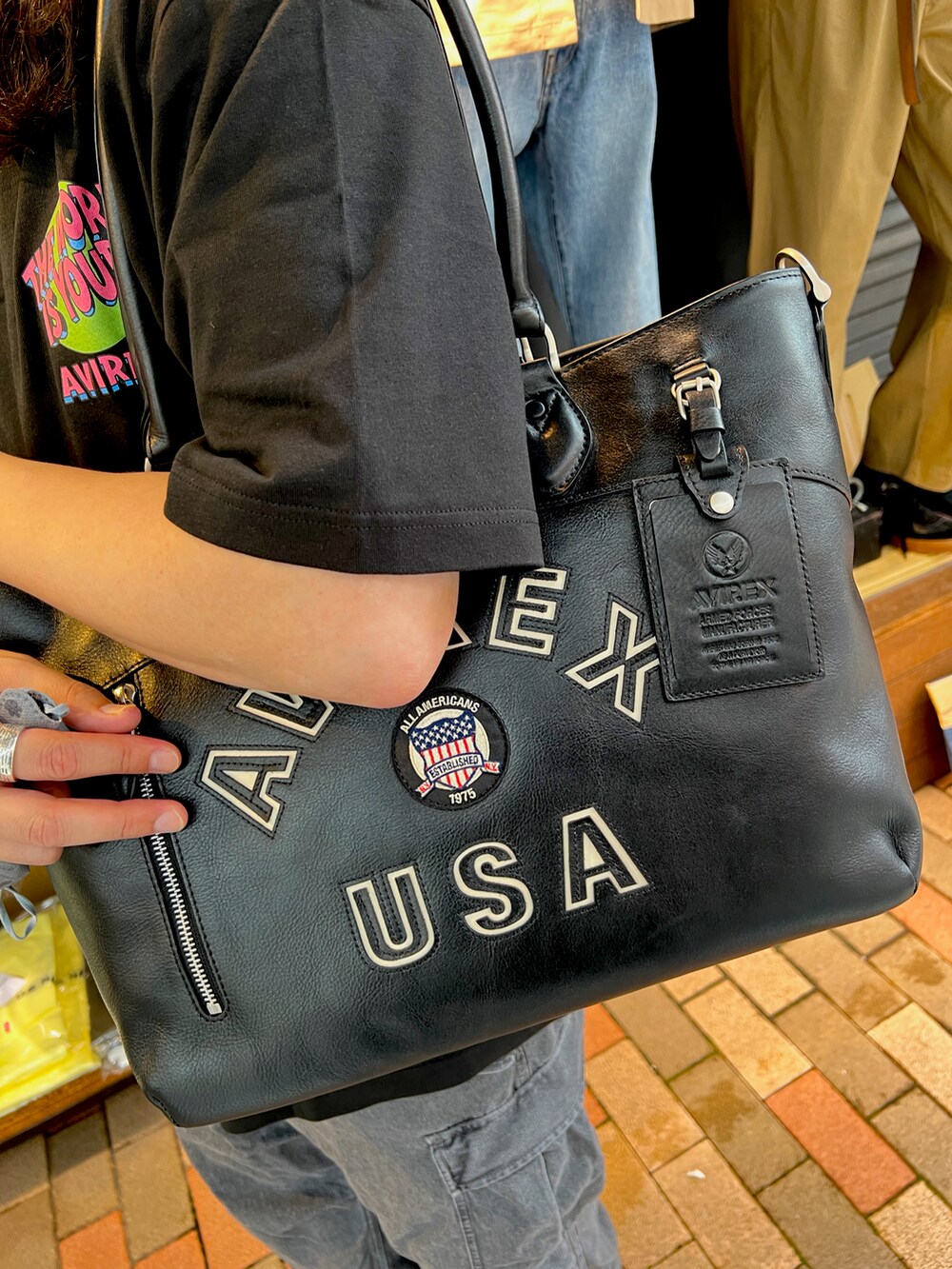 ブラック系のトートバッグ、ブラック系のカーゴパンツ、ブラック系のサンダルを着用したメンズの夏コーディネートの2枚目の写真