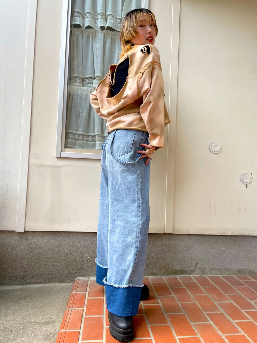 ブルー系のデニムパンツ、ベージュ系のスウェット、ブラック系のブーツを着用したレディースの春コーディネートの2枚目の写真