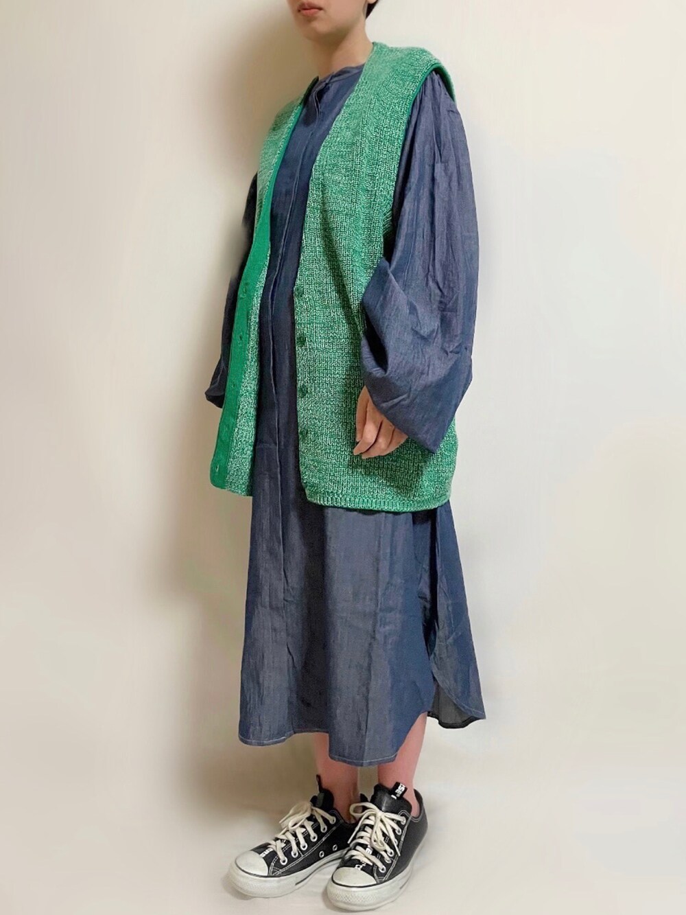 ブルー系のワンピース、グリーン系のベスト、ブラック系のスニーカーを着用したレディースの春コーディネートの2枚目の写真