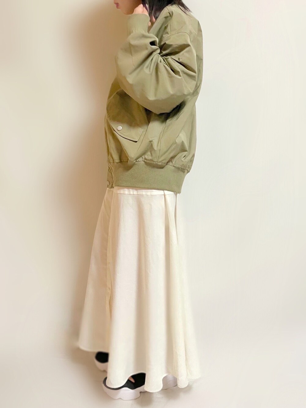 グリーン系のMA-1、ホワイト系のワンピース、ブラック系のスニーカーを着用したレディースの春コーディネートの3枚目の写真