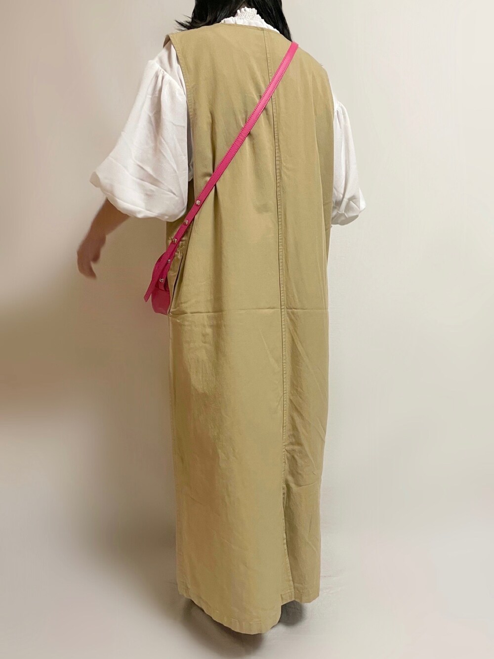 イエロー系のワンピース、ピンク系のショルダーバッグ、ブラック系のスニーカーを着用したレディースの春コーディネートの3枚目の写真