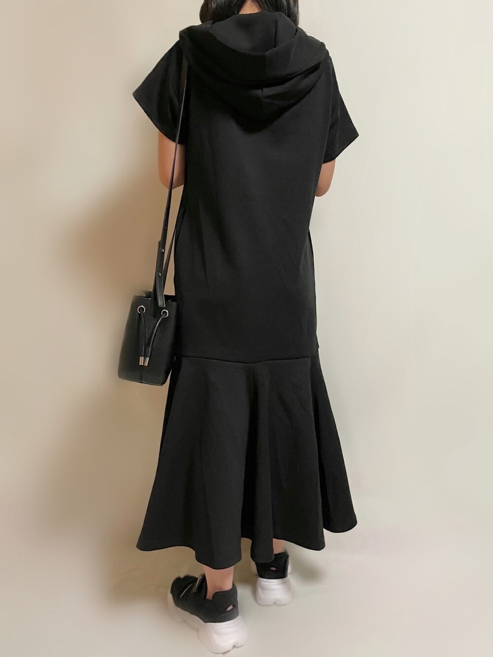 ブラック系のワンピース、ブラック系のショルダーバッグ、ブラック系のスニーカーを着用したレディースの春コーディネートの2枚目の写真