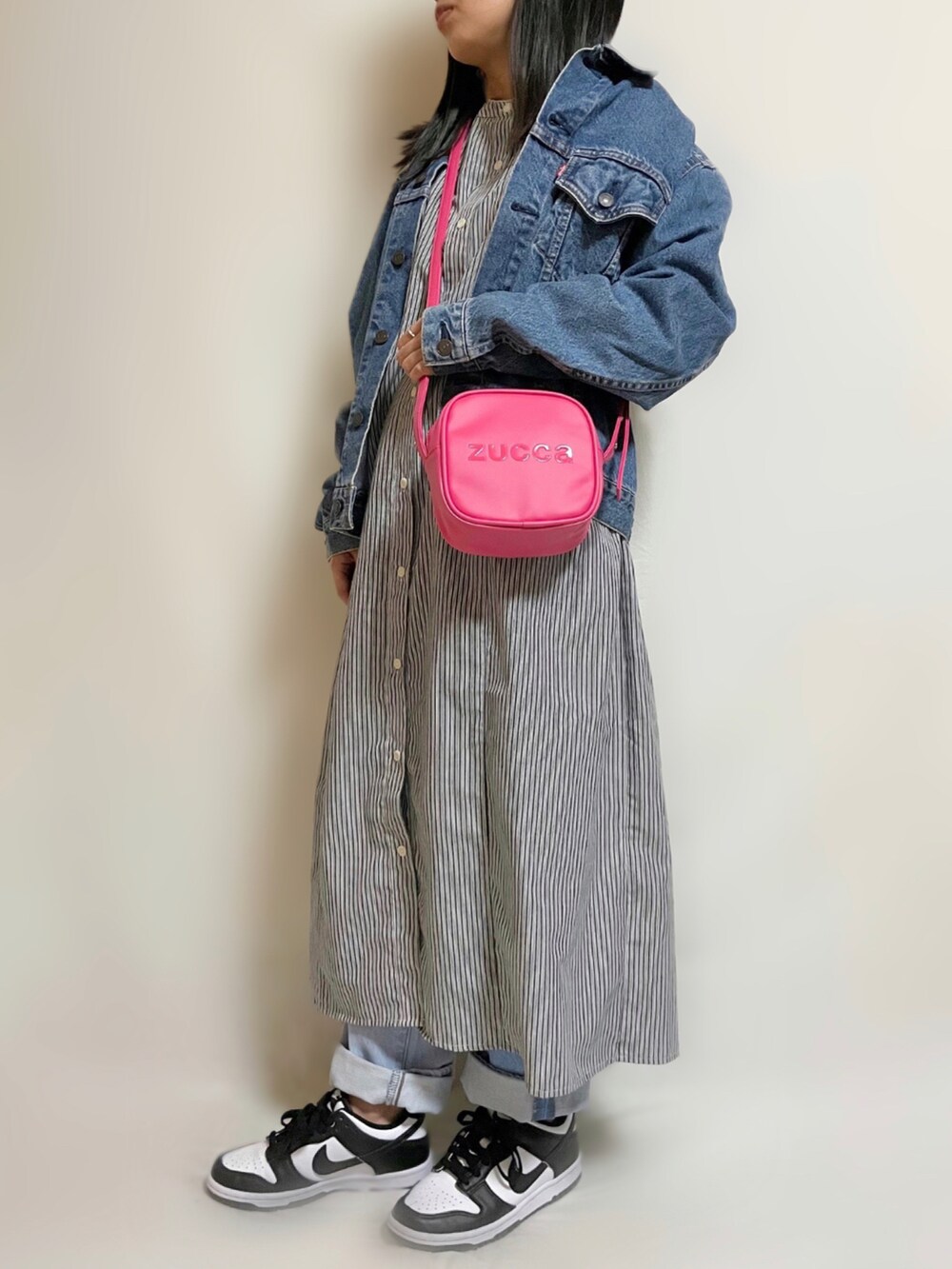 ブラック系のワンピース、ピンク系のショルダーバッグ、ブルー系のデニムジャケットを着用したレディースの春コーディネートの2枚目の写真