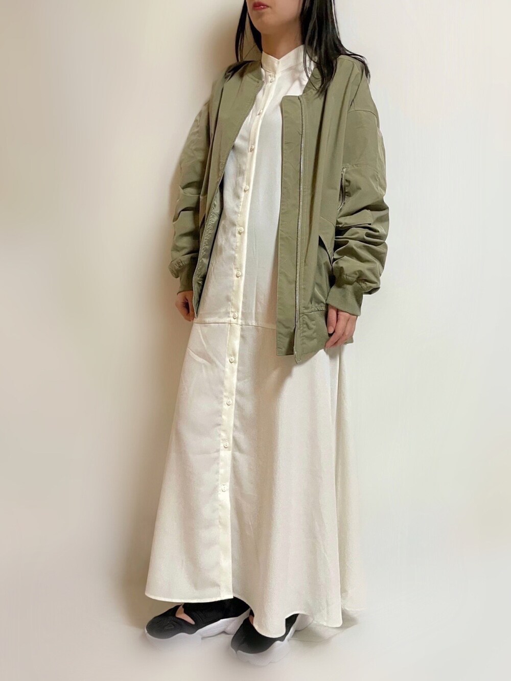 グリーン系のMA-1、ホワイト系のワンピース、ブラック系のスニーカーを着用したレディースの春コーディネートの2枚目の写真