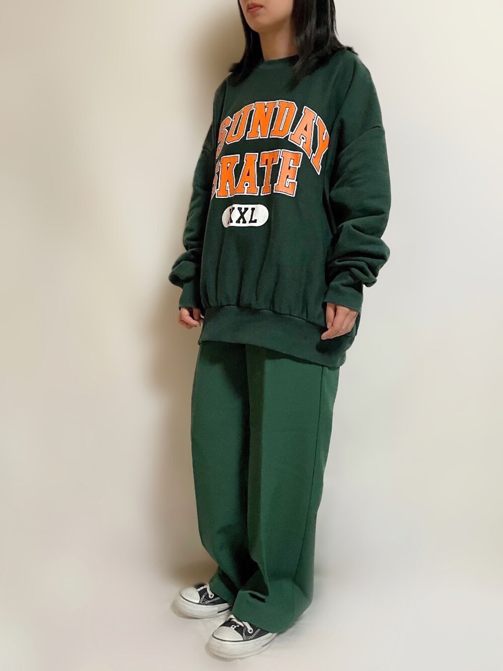 グリーン系のスウェット、グリーン系のスラックス、ブラック系のスニーカーを着用したレディースの冬コーディネートの2枚目の写真