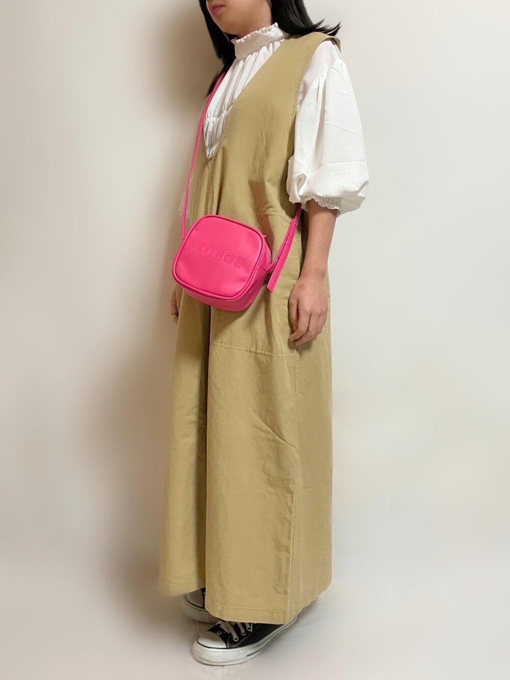 イエロー系のワンピース、ピンク系のショルダーバッグ、ブラック系のスニーカーを着用したレディースの春コーディネートの2枚目の写真