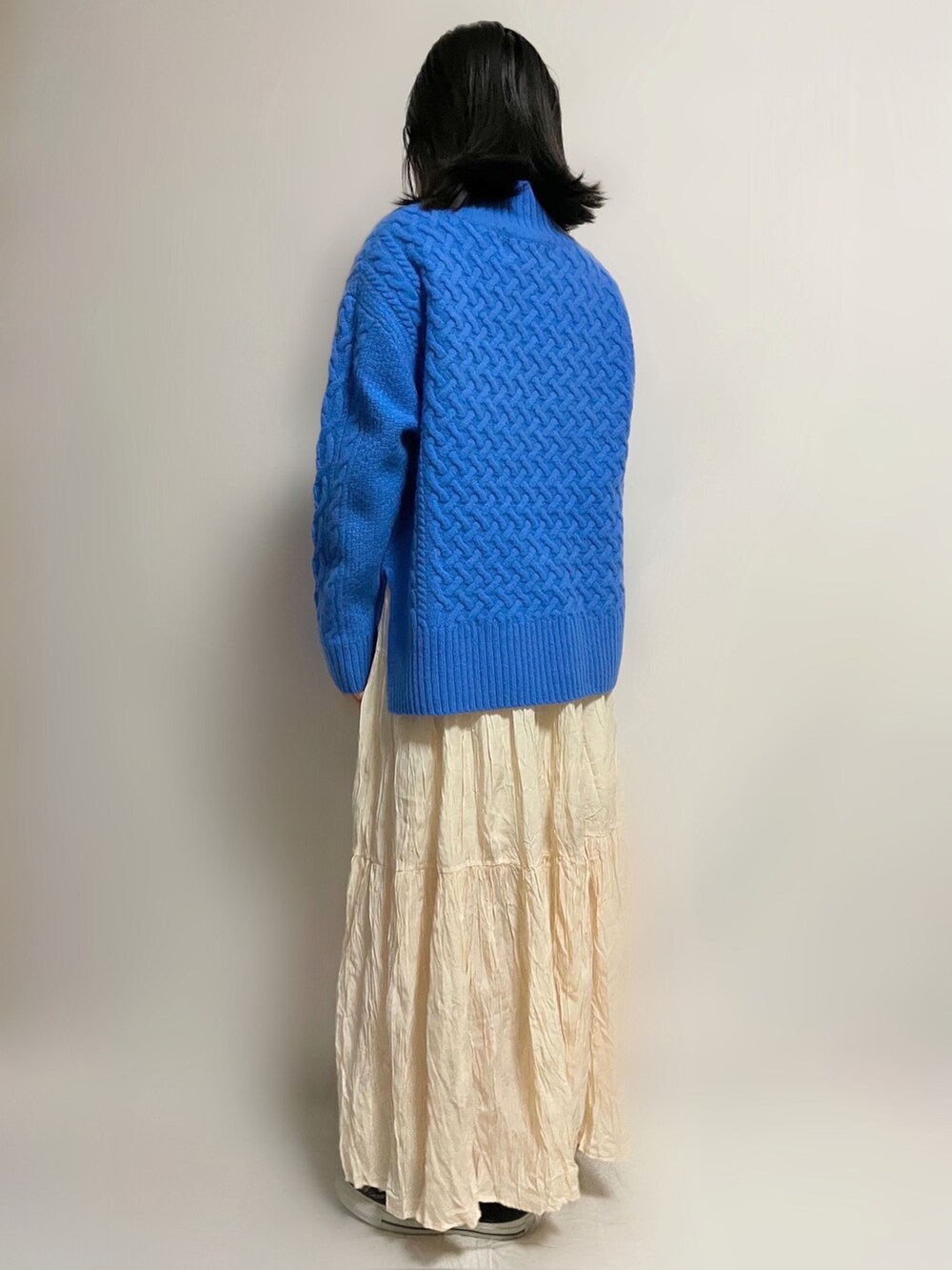 ブルー系のニット/セーター、ホワイト系のスカート、ブラック系のスニーカーを着用したレディースの秋コーディネートの2枚目の写真