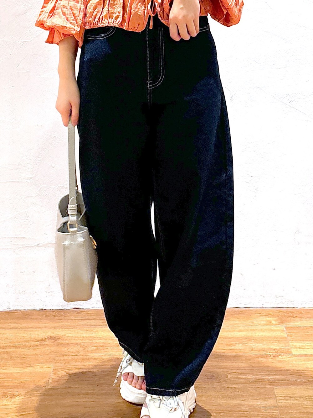 ブルー系のデニムパンツ、グレー系のショルダーバッグ、ホワイト系のサンダルを着用したレディースの春コーディネートの4枚目の写真