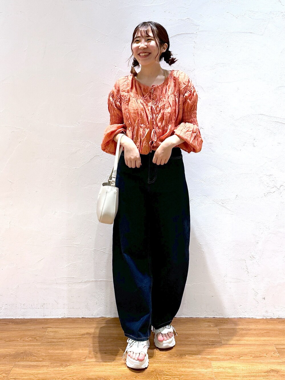 ブルー系のデニムパンツ、グレー系のショルダーバッグ、ホワイト系のサンダルを着用したレディースの春コーディネートの2枚目の写真
