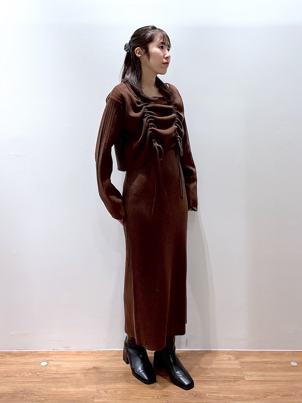 ブラウン系のワンピース、ブラック系のチェスターコートを着用したレディースの秋コーディネートの2枚目の写真