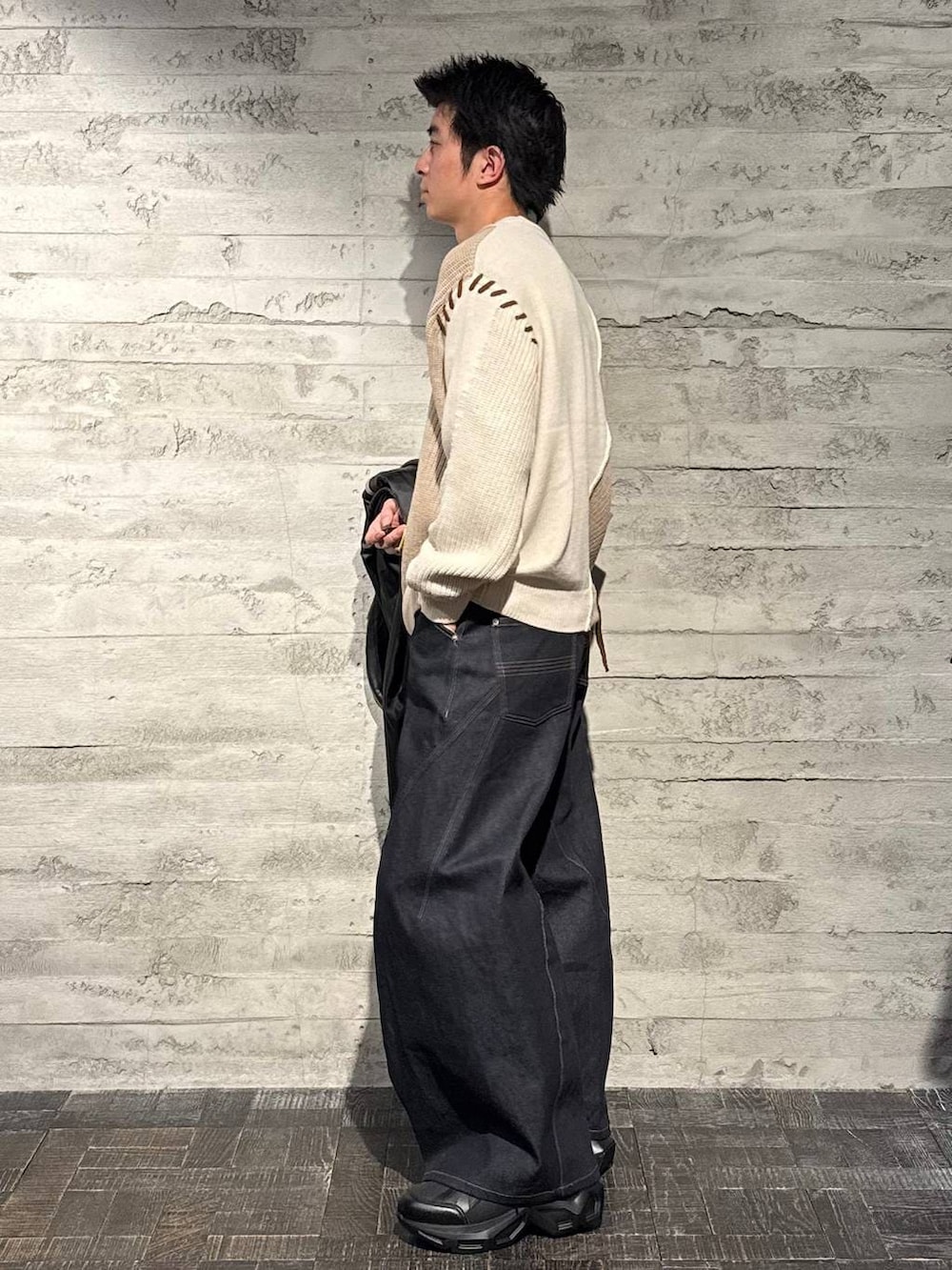 グレー系のトレンチコート、ブラック系のスニーカー、ホワイト系のニット/セーターを着用したメンズの秋コーディネートの6枚目の写真