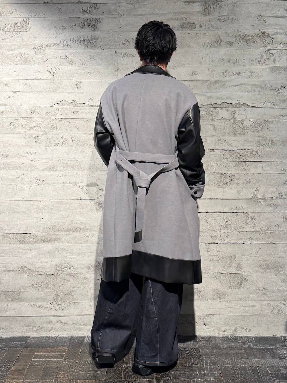 グレー系のトレンチコート、ブラック系のスニーカー、ホワイト系のニット/セーターを着用したメンズの秋コーディネートの3枚目の写真