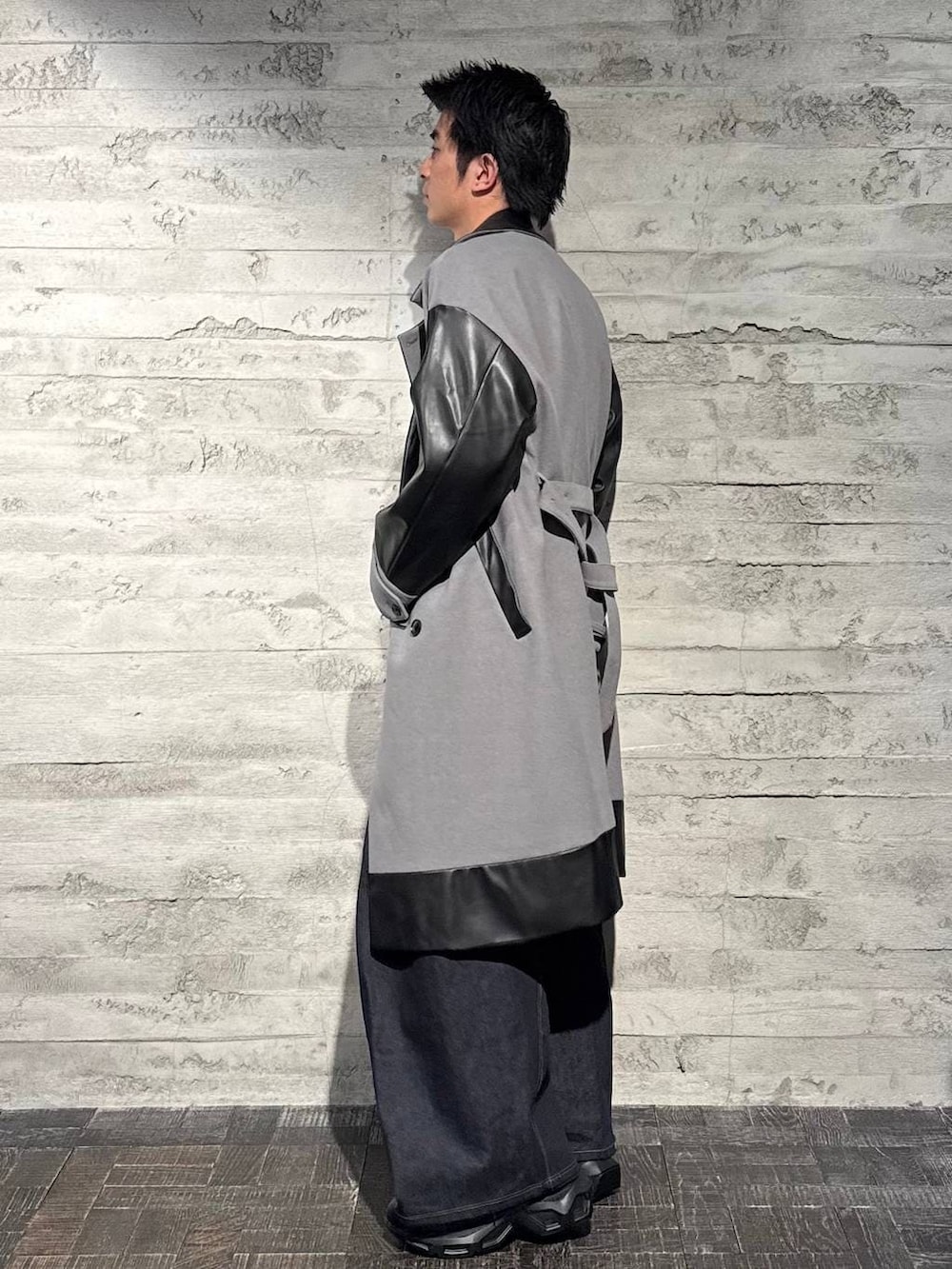 グレー系のトレンチコート、ブラック系のスニーカー、ホワイト系のニット/セーターを着用したメンズの秋コーディネートの2枚目の写真