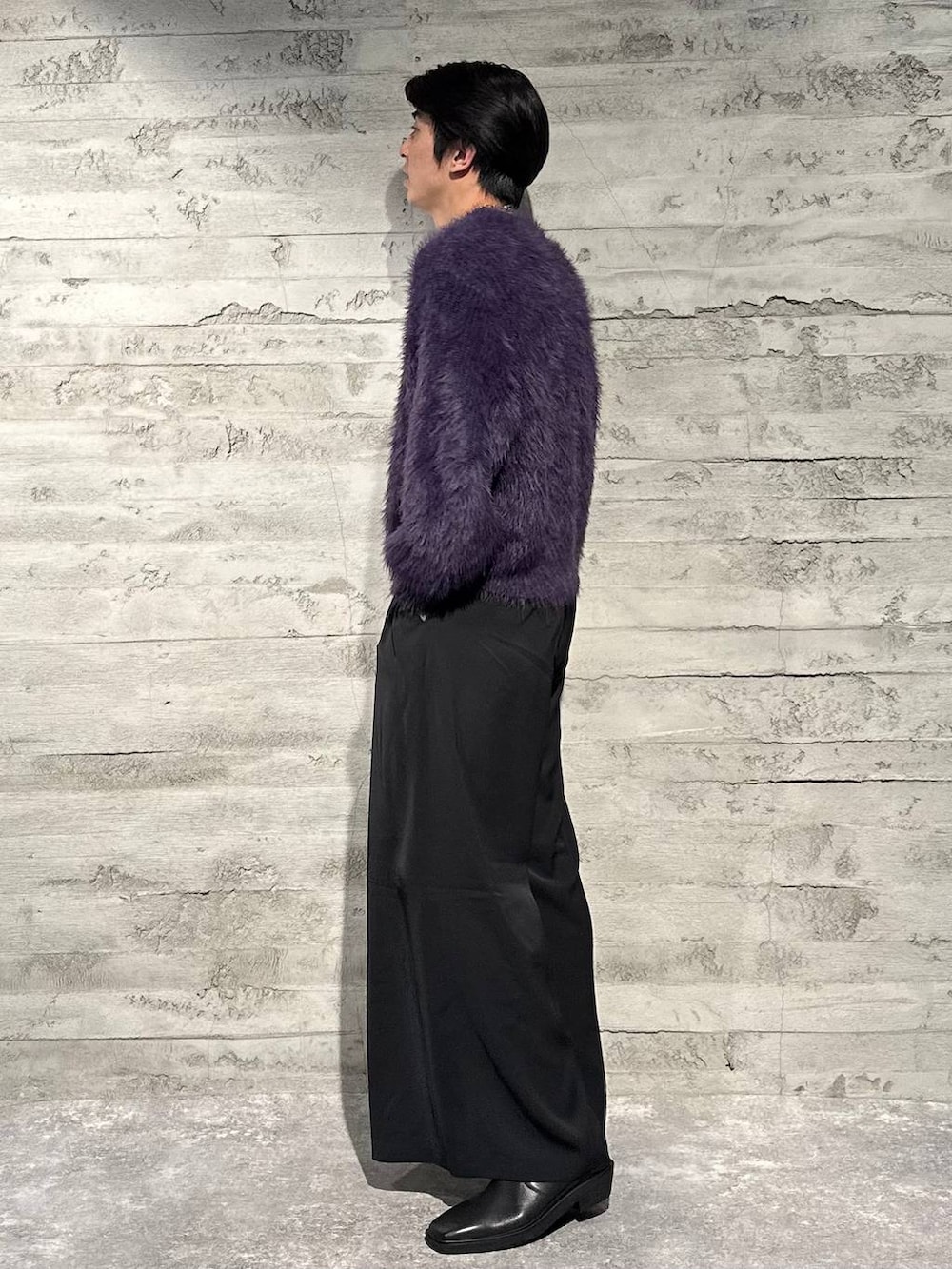 パープル系のニット/セーター、ブラック系のスラックス、ブラック系のブーツを着用したメンズの秋コーディネートの2枚目の写真