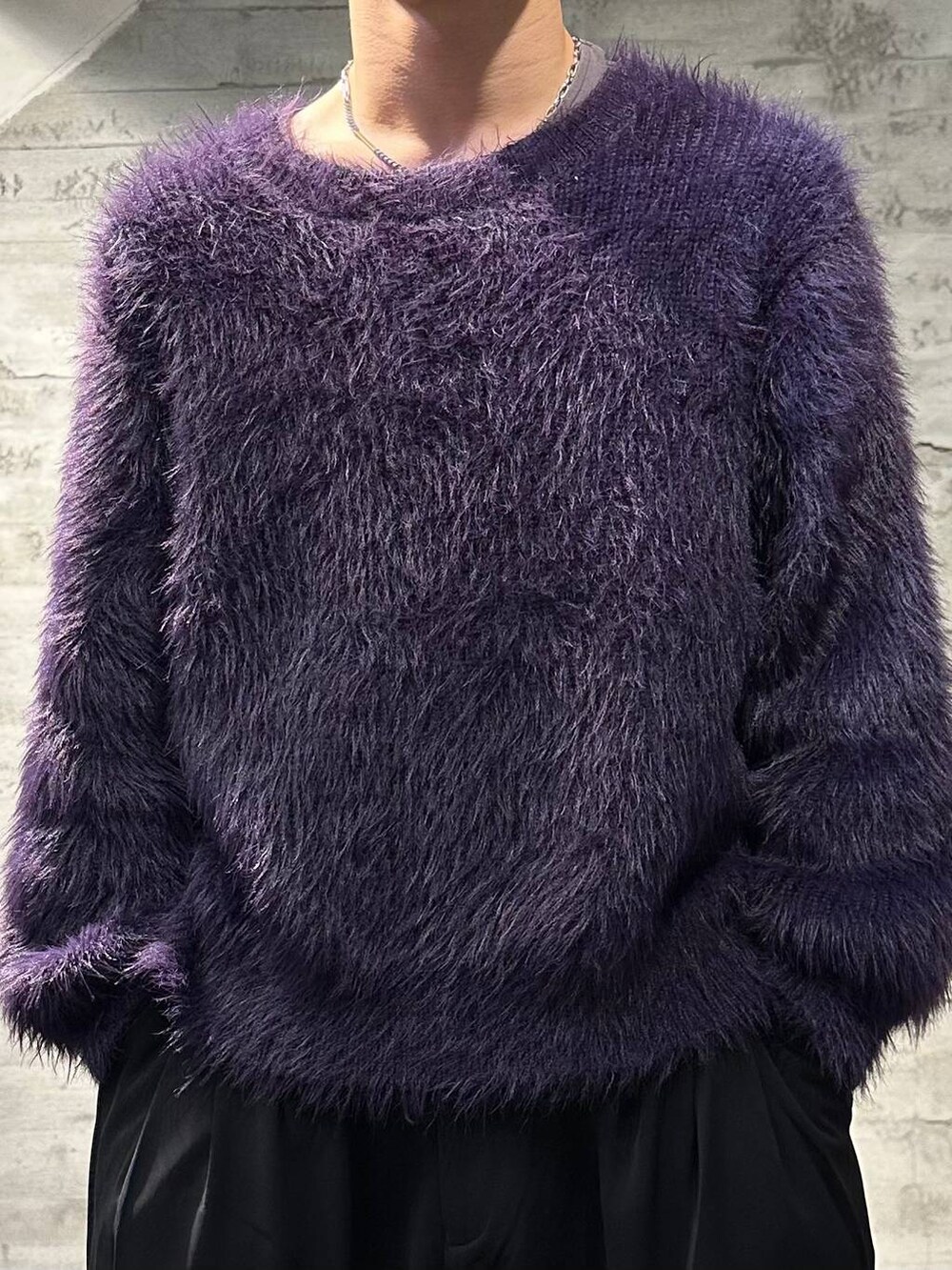 パープル系のニット/セーター、ブラック系のスラックス、ブラック系のブーツを着用したメンズの秋コーディネートの4枚目の写真