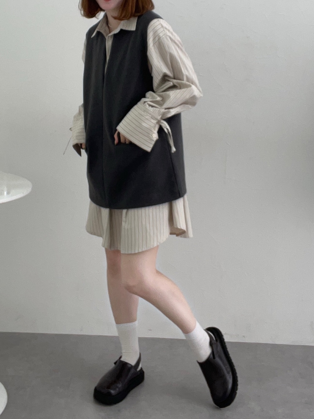 グレー系のベスト、ホワイト系のシャツ/ブラウスを着用したレディースの秋コーディネートの2枚目の写真