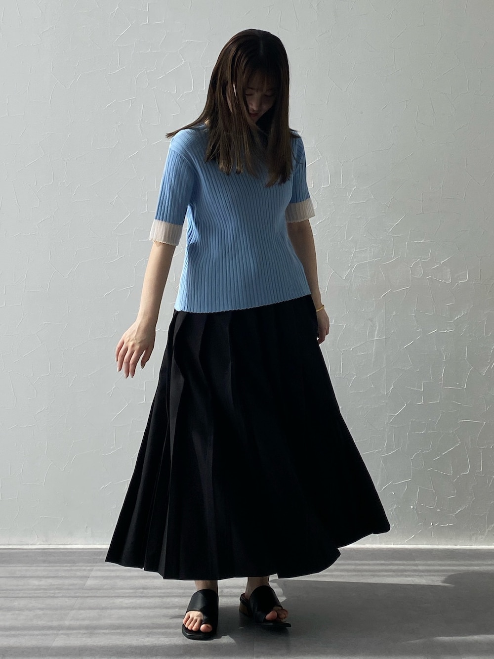 ブルー系のニット/セーター、ブルー系のニット/セーター、ブラック系のスカートを着用したレディースの夏コーディネートの2枚目の写真