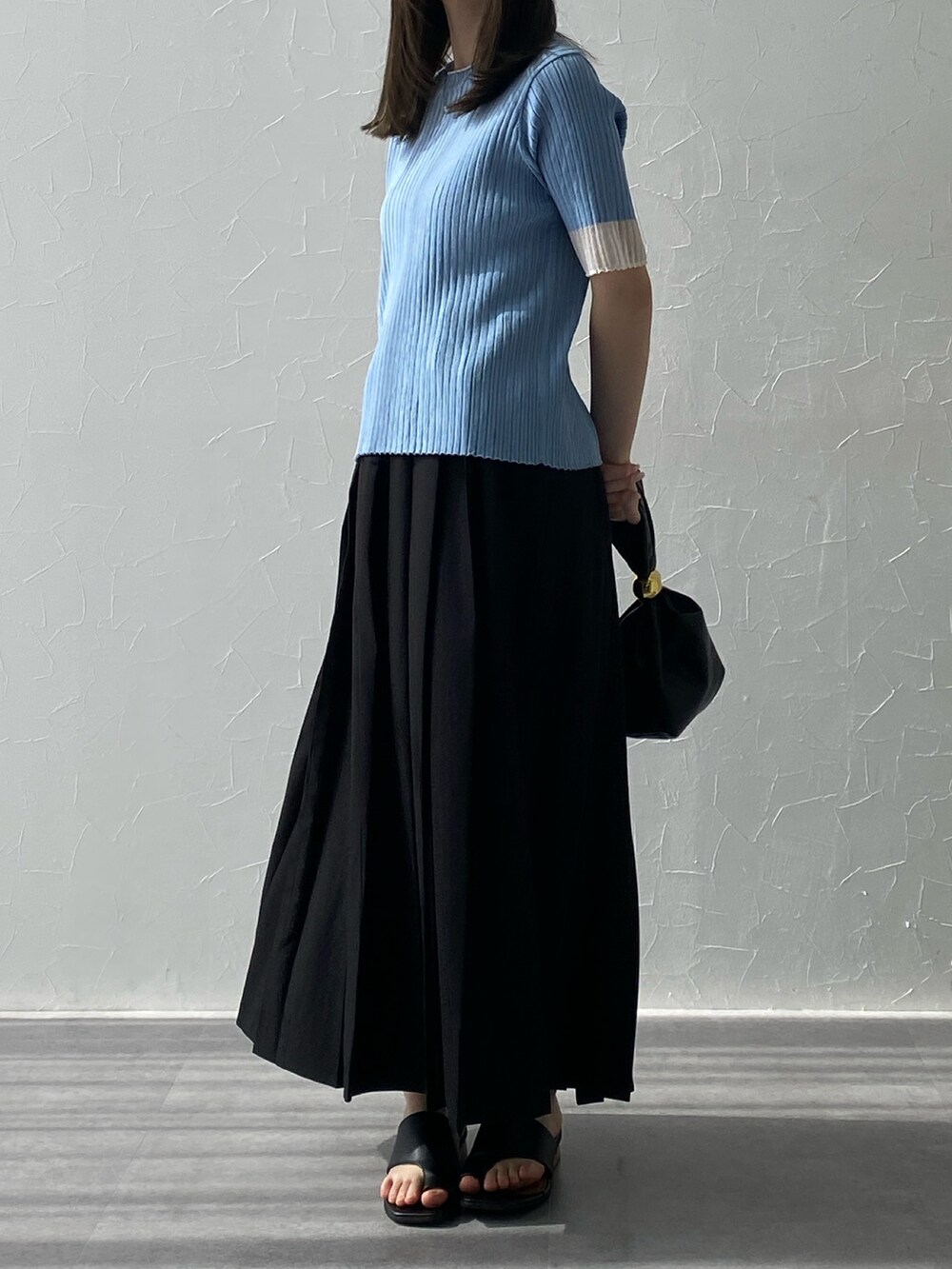 ブルー系のニット/セーター、ブルー系のニット/セーター、ブラック系のスカートを着用したレディースの夏コーディネートの3枚目の写真