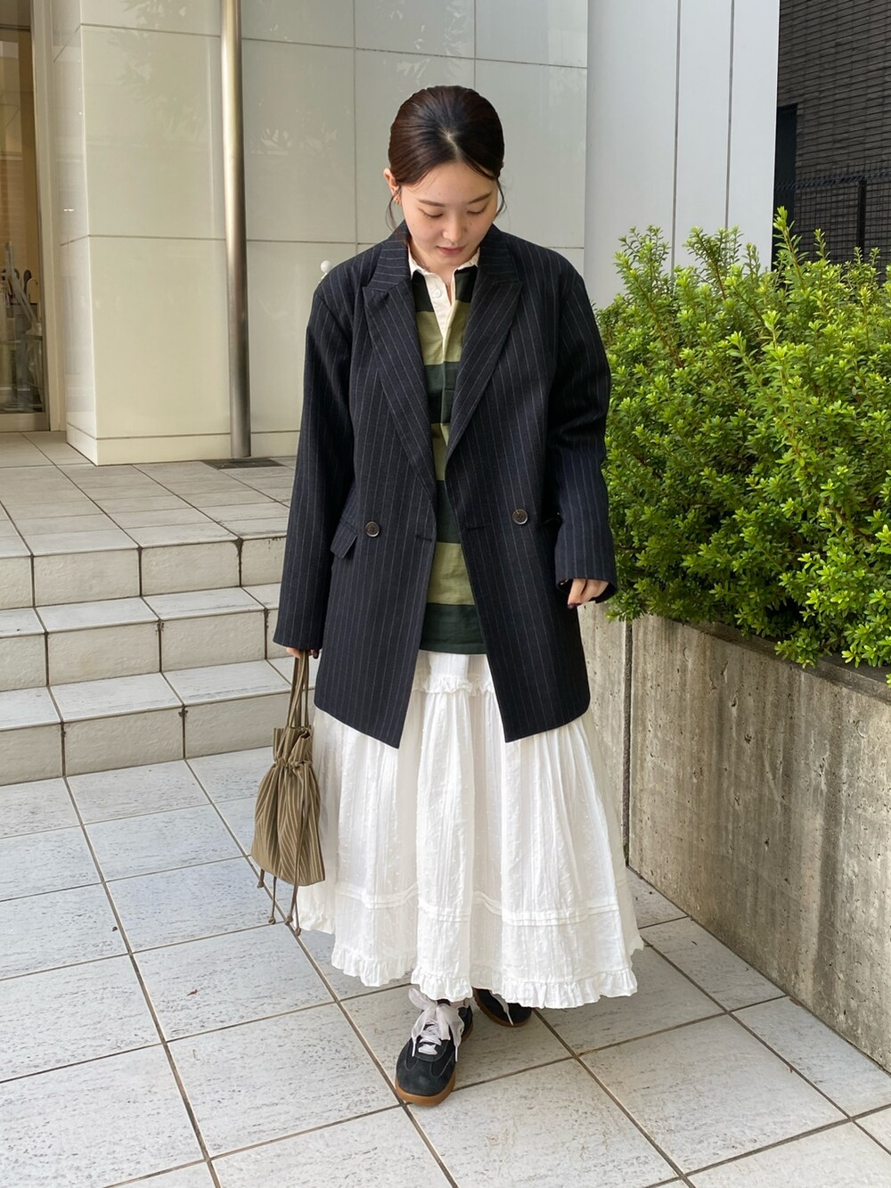 グレー系のテーラードジャケット、グリーン系のショルダーバッグを着用したレディースの秋コーディネートの2枚目の写真