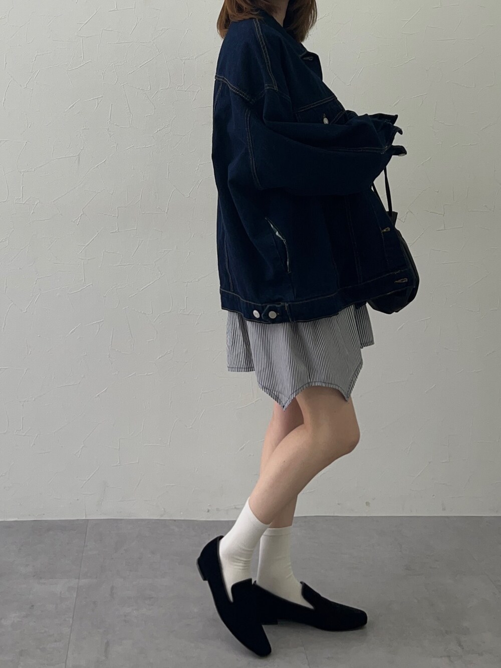 ブラック系のチュニック、ブルー系のデニムジャケット、ブルー系のデニムジャケットを着用したレディースの冬コーディネートの2枚目の写真